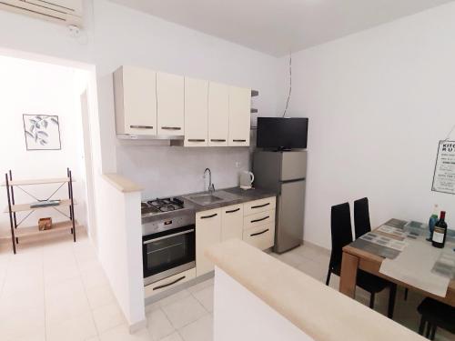 eine Küche mit weißen Schränken und einem Tisch und einem Herd in der Unterkunft Apartment MojMir 1 in Zavalatica