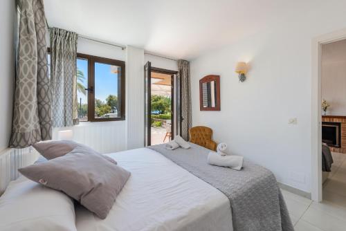 een slaapkamer met een groot wit bed en een raam bij Apartment La Bugambilia in Port de Pollença