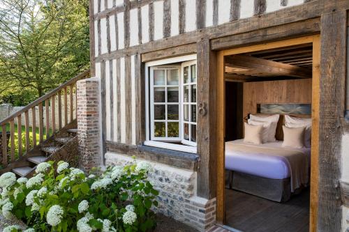 Ce lit se trouve dans une maison en bois dotée d'une fenêtre. dans l'établissement Hôtel Saint-Delis - La Maison du Peintre - Relais & Châteaux, à Honfleur