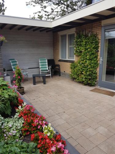 a patio with two chairs and flowers in front of a house at Achter de Beukenboom in Roden