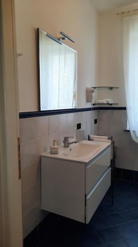a white bathroom with a sink and a mirror at B&B Ai Tre Cavalli in Cherasco