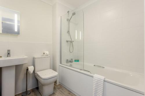 een witte badkamer met een toilet en een douche bij Sanderling in Poole