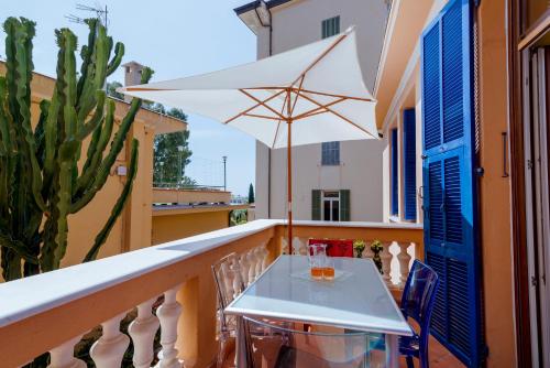 een witte tafel op een balkon met een witte parasol bij Villa Vallone Apartment in Bordighera