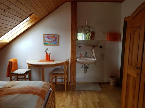 Schlafzimmer mit einem Bett, einem Waschbecken und einem Tisch in der Unterkunft Gästezimmer Aschenbrenner in Bad Rodach