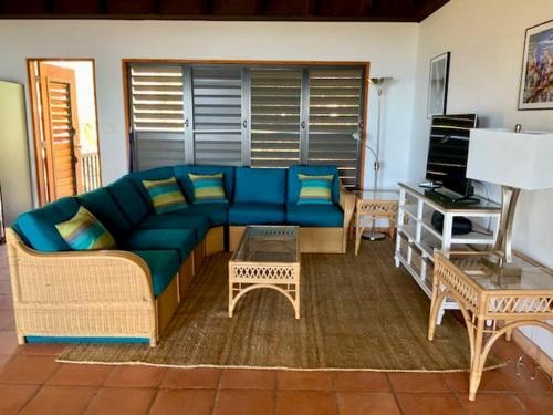 a living room with a blue couch and a table at VILLA DEL SOLE in Virgin Gorda