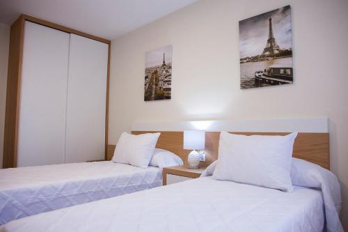 Habitación de hotel con 2 camas con sábanas blancas en Laros Pios Alojamiento, en Vilalba