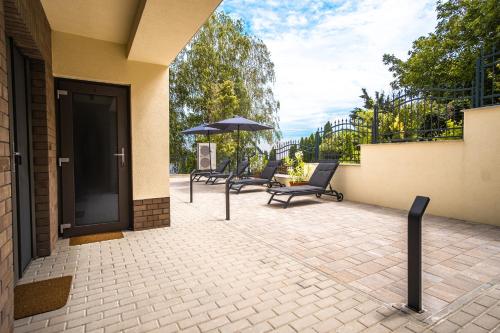 a patio with three chairs and an umbrella at Kiss-Henézi Guest House in Keszthely