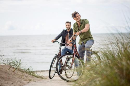 two men riding a bike on the beach at SPA Amber Palace in Šventoji