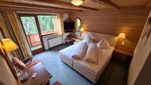a hotel room with a bed and a desk and a chair at Hotel Cresta in Samnaun