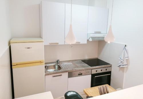 Elle comprend une petite cuisine avec des placards blancs et un évier. dans l'établissement Apartments Valiža 2, à Senj