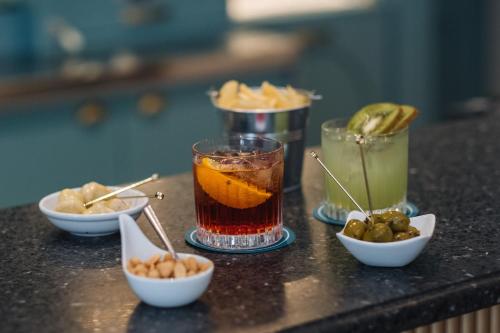 a table with three drinks and bowls of food at Hotel Indigo Verona - Grand Hotel Des Arts by IHG in Verona