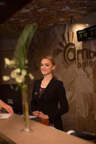 a woman standing at a table in front of a sign at SPA Amber Palace in Šventoji