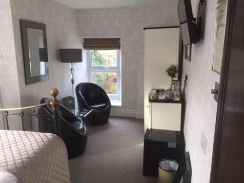 a bedroom with a bed and a chair and a window at Glenville House - Adults Only - Incl FREE off-site health club with swimming pool, hot tub, sauna & steam room in Windermere