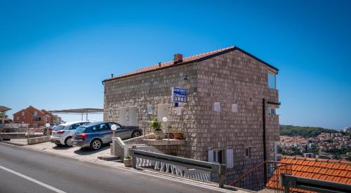a brick building with cars parked in a parking lot at Apartments Dilberovic in Dubrovnik
