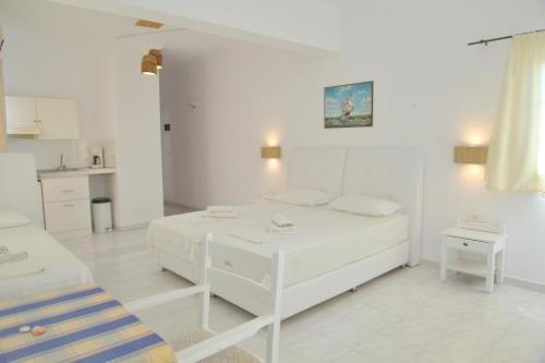 a white room with a bed and a kitchen at Giannis Hotel Apartments in Adamantas