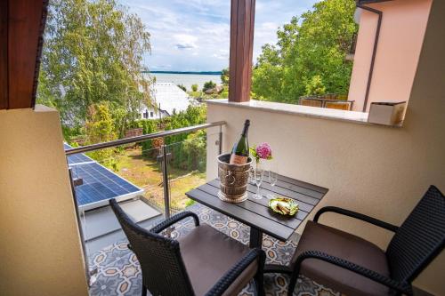 a balcony with a table and a bottle of wine at Kiss-Henézi Guest House in Keszthely