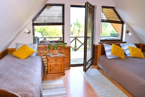 two beds in a room with two windows at Sodyba Basapėdė in Bijutiškis
