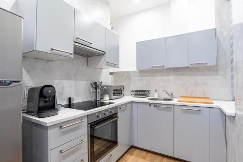 une cuisine blanche avec des armoires blanches et des appareils en acier inoxydable dans l'établissement Appartement Familial Centre Ville de Strasbourg, à Strasbourg