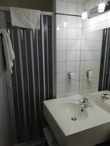 une salle de bain blanche avec un lavabo et un miroir dans l'établissement Hôtel Du Manoir, à Tours