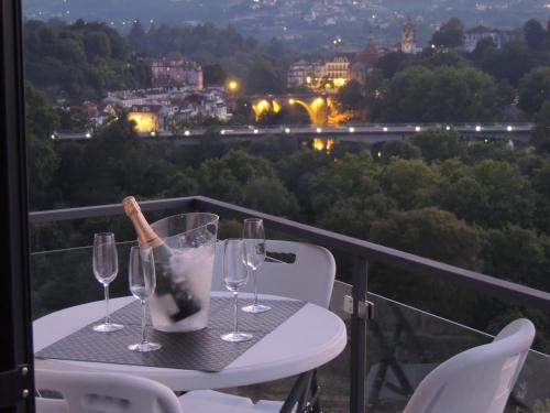 a table with wine glasses and a bottle on a balcony at Apartamento Amarante - Vista São Gonçalo in Amarante