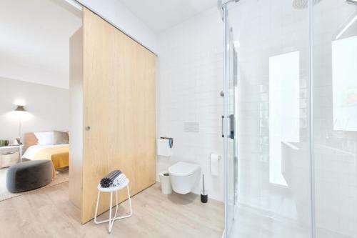 a bathroom with a shower and a toilet and a bed at Art Home Apartments in Aveiro