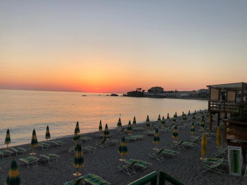 a beach with chairs and umbrellas at sunset at La Risacca Relais in Belvedere Marittimo