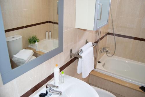 a bathroom with a sink and a mirror and a tub at Apartamento Cabo de Gata in Retamar