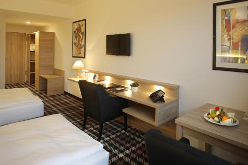 una camera d'albergo con scrivania e letto e una camera di Hotel PreMotel-Premium Motel am Park a Kassel