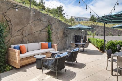 a patio with a couch and tables and chairs at Ayres Hotel Vista Carlsbad in Vista
