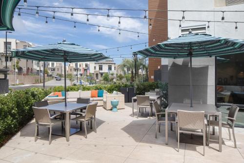 a patio with tables and chairs and umbrellas at Ayres Hotel Vista Carlsbad in Vista