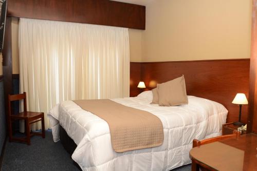 Habitación de hotel con cama y mesa en Hotel Leoncia, en Colonia del Sacramento
