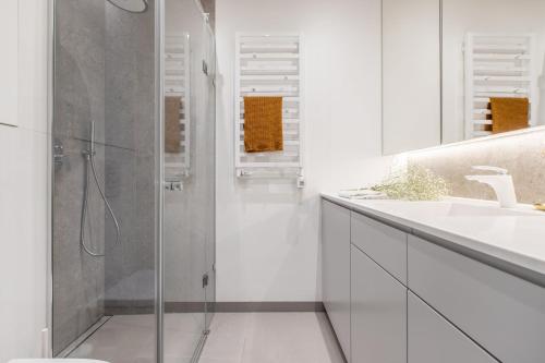 een witte badkamer met een douche en een wastafel bij Apartament MIŁOSZA in Ełk