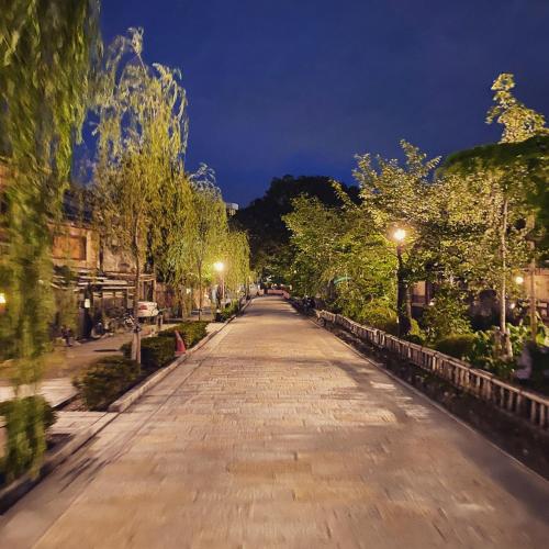 an empty street at night with trees and lights at JAM Hostel Kyoto Gion in Kyoto