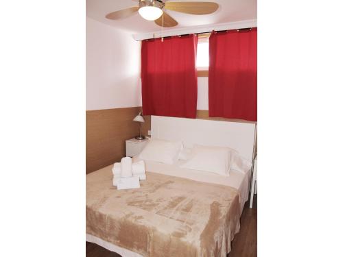 プラヤ・デル・イングレスにあるAloe Friendly Holiday Homeのベッドルーム1室(赤いカーテンと天井ファン付きのベッド1台付)