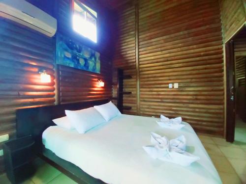 a bedroom with a white bed with two flowers on it at Horizon Hotel & Yoga Center in Santa Teresa Beach