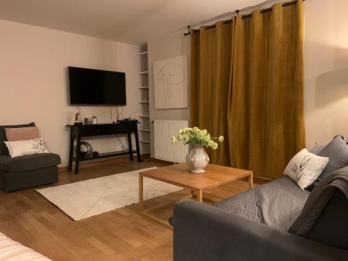 ein Wohnzimmer mit einer Couch und einem Tisch und einem Fernseher in der Unterkunft Luxury Appartement Disneyland in Magny-le-Hongre