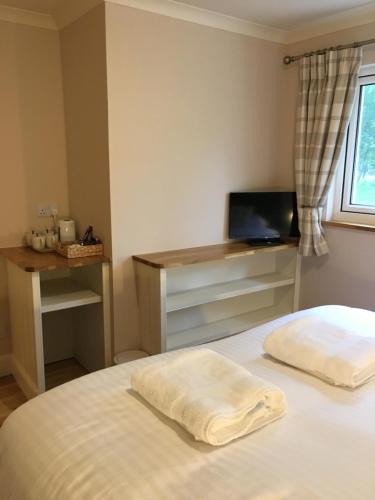 a bedroom with a bed with a desk and a television at East Park B&B in Roybridge