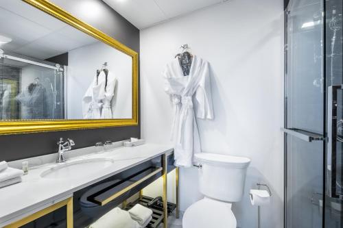 ein Badezimmer mit einem Waschbecken, einem WC und einem Spiegel in der Unterkunft Hotel Clarendon in Québec
