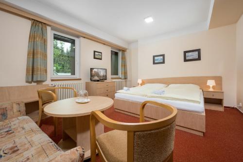 ベドジホフにあるHorský Hotel Jelínekのベッドとテーブルが備わるホテルルームです。