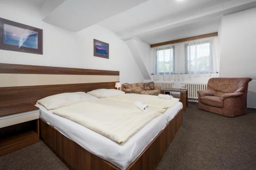 a bedroom with a large bed and a chair at Horský Hotel Jelínek in Bedřichov