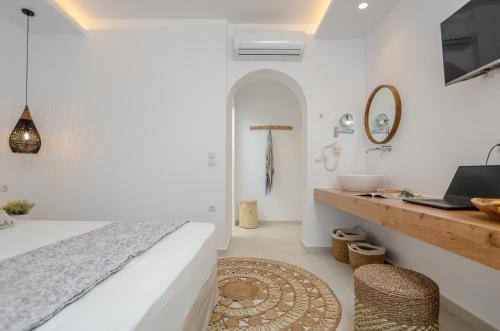 a bedroom with a bed and a desk with a laptop at Sea & Olives Suites Hotel and Villas in Plaka