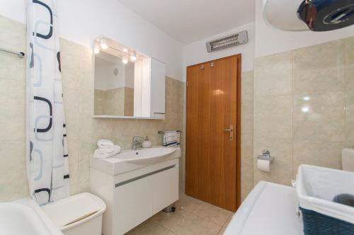 uma casa de banho com um lavatório, um WC e um espelho. em Apartment Luna em Omiš
