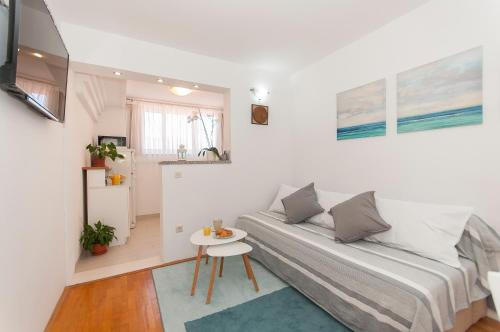 um pequeno quarto branco com uma cama e uma mesa em Apartment Luna em Omiš