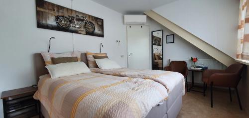 1 dormitorio con cama, mesa y escalera en B&B Knooppunt70, en Arcen