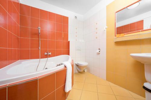 a bathroom with a tub and a toilet and a sink at Horský Hotel Jelínek in Bedřichov