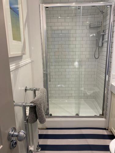 a shower with a glass door in a bathroom at Little Dolly sea view 2 bedroom apartment, St Ives town, dog friendly in St Ives