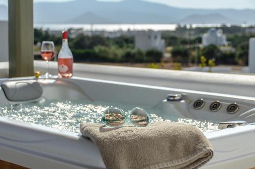 a bath tub with a pair of glasses and a bottle of wine at Sea & Olives Suites Hotel and Villas in Plaka