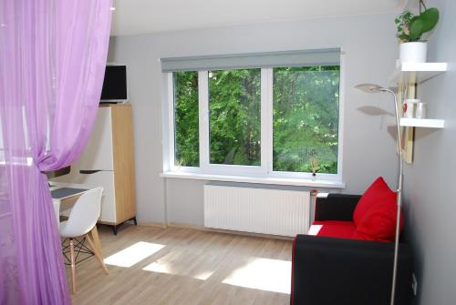 a living room with a red couch and a window at Phoenix apartment in Jūrmala