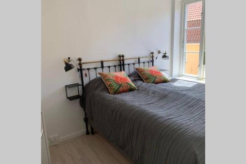 ein Schlafzimmer mit einem Bett mit zwei Kissen und einem Fenster in der Unterkunft Lejlighed på Torvet i Stege in Stege