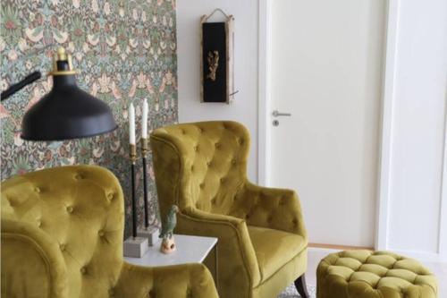 a living room with two yellow chairs and a lamp at Lejlighed på Torvet i Stege in Stege